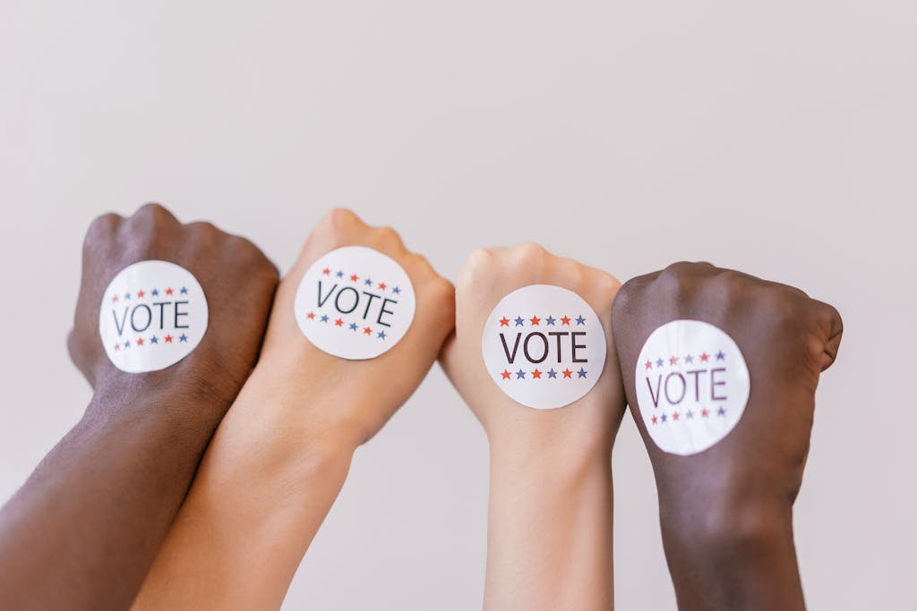 Close-up of diverse hands showing unity with vote stickers emphasizing democracy.